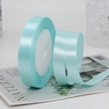 Light blue 1.5cm satin ribbon roll for gift wrapping on a magazine background - Light Blue