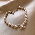 Dettaglio di elegante bracciale di perle a farfalla con micro-pave su raso dorato - Braccialetto di Perle con Motivo a Farfalla / Argento con Rosa