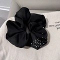 Detailed view of a black satin hair scrunchie with sparkling rhinestones on fabric - Black