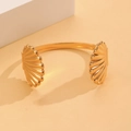Detalle de un brazalete dorado con forma de concha y texturas acanaladas - Pulsera de Concha Doble (7092)