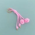 Close-up of pink hand-woven nylon bag charm with golden metal ring and ball knot details - Pink