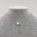 Collana con ciondolo a perla singola su catena dorata esposta su supporto in velluto grigio - Perla Singola da 7MM