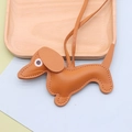 Close-up of brown litchi grain leather dachshund charm with stitching on a wooden tray - Earthy Yellow