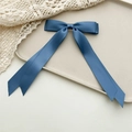 Detailed view of elegant navy blue satin ribbon bow hair clip on a minimalist tray - Blue