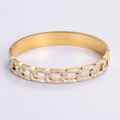 Vista detallada de un brazalete dorado con textura de cadena, pedrería pavé y diseño abierto - Dorado