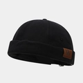 Detailed close-up of a black canvas brimless docker hat with a brown leather W-letter label - Adjustable / Letter W Patch Black