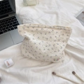 Detail of floral seersucker toiletry bag with zipper and logo in a lifestyle setting - Beige Purple Flower