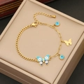 Makro-Detail des goldenen Armbands mit blauem Emaille-Schmetterling und Evil Eye - Schmetterling