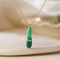 Dettaglio macro della catena dorata con ciondolo in smalto verde stile bambù - Lettera I