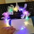 Close-up of white feather glowing headband with colorful LED lights held by hand - Flower Garland / Goose Feather White Colorful Light