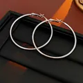 Primo piano di grandi orecchini a cerchio in argento lucido su supporto nero testurizzato - 5CM di diametro / Perno in Argento-Argento (5cm)