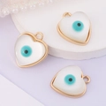 Detailed view of three white heart-shaped evil eye pendants with golden metal edges - Heart
