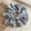 Detail of grey knitted hair scrunchie with a brown bow and small gold pendant charm - Gray
