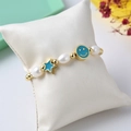 Détail du bracelet en perles avec pendentifs étoile et visage souriant en émail bleu - Bleu Foncé/Or