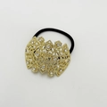 Detail eines goldenen Blumen-Haargummis mit Perlen und Steinen auf schwarzem Elastikband - Gold