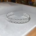 Detailopname van de zilveren opengewerkte bloemenarmband met gepolijste metalen glans - Zilver