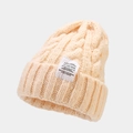 Detail of warm beige cable knit beanie showing thick texture and decorative patch - Orange Pink