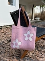 Detailed texture of pink knitted tote bag featuring white floral applique on a wooden chair - Pink