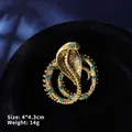 Macro shot of a golden cobra snake brooch with green crystals measuring 4.0 by 4.3 cm - Gold Snake Ring with Green Eyes (XZ24148)