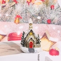 Detail eines schneebedeckten Miniatur-Hauses aus Harz mit roter Tür und Tannenbäumen - Stil D (Kirche)