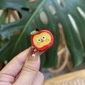 Cute red apple hair clip with cartoon face and green leaf shown in a hand close-up - Red Apple with Yellow Center