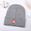 Dettaglio del ricamo a fungo su un berretto in maglia grigia con trama invernale - Taglia unica / Grigio
