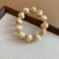 Vue détaillée de perles de marbre crème et anneaux dorés sur un bracelet rétro chic - Bracelet / Blanc