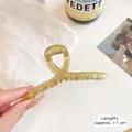 Large amber matte shark hair claw clip 11cm length shown held in hand in lifestyle setting - 11cm / Green