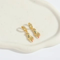 Detailed macro shot of gold palm earrings with evil eye center and pink nail accents - Blue