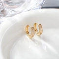 Macro view of gold huggie earrings featuring three rows of sparkling zircon stones - 14x14mm / Gold