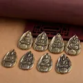 Detail view of eight vintage brass Buddhist guardian deity pendants in teardrop shape - 8 Buddha Statues