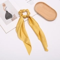 Detail of yellow satin hair scrunchie with long ribbon on a stylish magazine and tray - Yellow