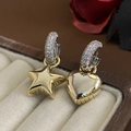 Dettaglio macro di orecchini asimmetrici dorati con stella, cuore e zircone bianco - Chiusura per orecchini asimmetrica / Oro