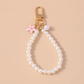 Detalle de llavero de perlas con colgante de flor esmaltada rosa y herrajes dorados - Rosa