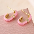Detailed view of U-shaped gold earrings with pink enamel coating and sparkling zircon stone - Pink