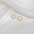 Close-up of gold hoop earrings with pink enamel dots on white silk fabric - Light Purple