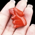 Miniature red natural stone rabbit figurine hand-held against a dark background - Red Jasper