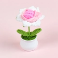 Close-up of handmade crochet rose in a white ceramic pot with soft pink background - Gradient Glitter
