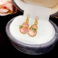 Pink gourd earrings with gold frame and pearls displayed in a grey velvet jewelry box - Pink Gourd Style (HE27510)