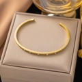 Elegant gold open bangle with five sparkling cubic zirconia stones on jewelry box - Gold 5-Stone Open Bangle