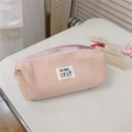 Detailed view of pink corduroy pouch with 'best' floral patch on a white tabletop - Twill Skin Pink