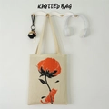 Detail of beige knitted tote bag with orange cat and flower motifs on a wall hook - Cream Cotton Print