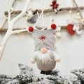 Grey Christmas gnome plush ornament with red pom-pom hat and star embroidery hanging on a tree - Gray