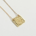 Close-up of golden Saint Benedict medal pendant with a hammered square base on white leather - Square Letter (Gold)