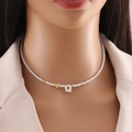 Shell beaded necklace with gold heart and white letter Q charm on a model's neck - Letter Q
