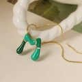 Dettaglio del ciondolo con lettera in smalto verde su catena a scatola dorata strutturata - M