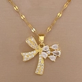 Dettaglio del ciondolo a farfalla dorato di lusso con zirconi su sfondo di seta beige - Ciondolo Fiocco a Goccia d'Acqua in Zirconia (E423)