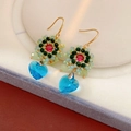Detailaufnahme von Vintage-Ohrringen mit roten Edelsteinen und hellblauen Herz-Anhängern - Blau
