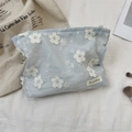 Primer plano del neceser de tela azul claro con bordado floral y etiqueta tejida - Azul