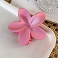 Macro detail of a pink frangipani hair claw clip on a white tray with straw background - Pink Flower